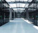 Large enterprise data center with rows of black server racks under a vaulted ceiling